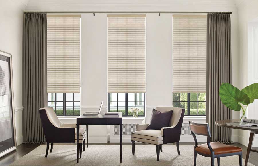 home office with neutral roller shades paired with dark green pinch pleat curtains 